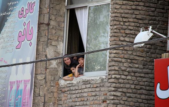 دو کودک همراه با یک زن در حال تماشای اجرای حکم اعدام ۳ مرد از پنجره منزلشان هستند. (مشهد/ ۶ خرداد ۱۳۹۴) عکس از خبرگزاری مهر